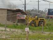 Trator destrói as construções irregulares no terreno invadido