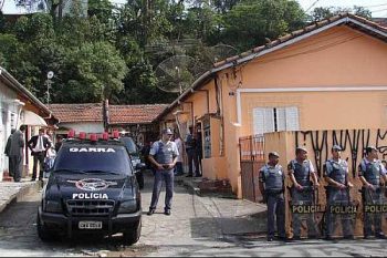 Policiais em frente à casa onde os meninos foram mortos, durante a reconstituição do crime