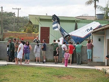 Moradores observam o pequeno avião que caiu no pátio de uma casa em Blumenau, sem deixar feridos