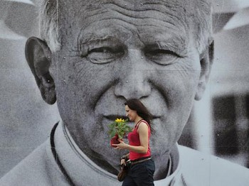 Fiel passa diante de imenso retrato do Papa João Paulo II na Cracóvia, Polônia, na quinta (28)