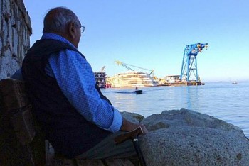 Homem observa, a partir da ilha italiana de Giglio, os trabalhos no naufragado navio Costa Concordia, nesta terça-feira (24)