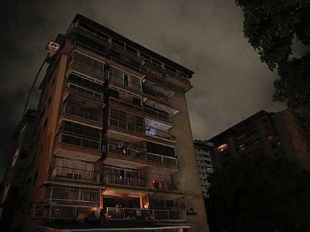 Um homem espera, na varanda de seu apartamento em Caracas, a volta da energia elétrica.