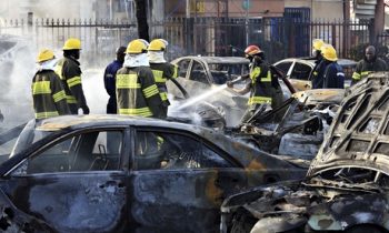 Bombeiros apagam fogo de carros após explosão de uma bomba no shopping na capital nigeriana